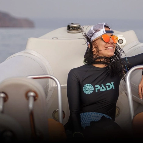 Smiling dive instructor relaxing on a boat after training, representing authentic storytelling in dive marketing and emotional connection with divers.