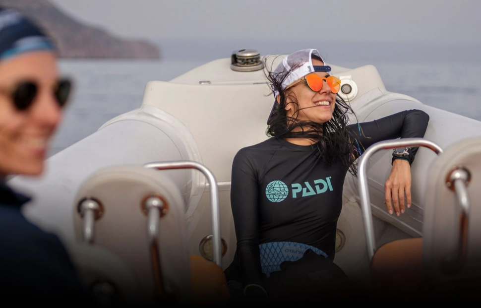 Smiling dive instructor relaxing on a boat after training, representing authentic storytelling in dive marketing and emotional connection with divers.