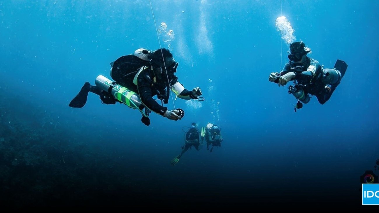 Two Tec Divers working together underwater during a decompression stop in Roatán, representing the teamwork and precision of a Tec Safety Diver.