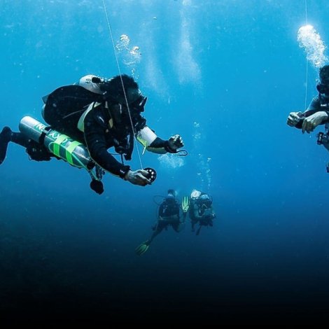 Two Tec Divers working together underwater during a decompression stop in Roatán, representing the teamwork and precision of a Tec Safety Diver.