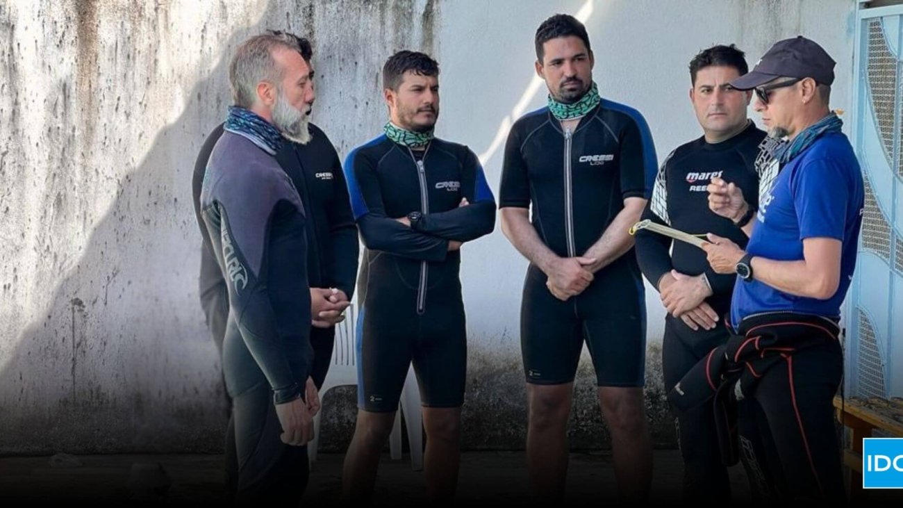 Confident scuba diving instructor leading a dive briefing with students before entering the water, representing leadership in the competitive dive instructor job market.
