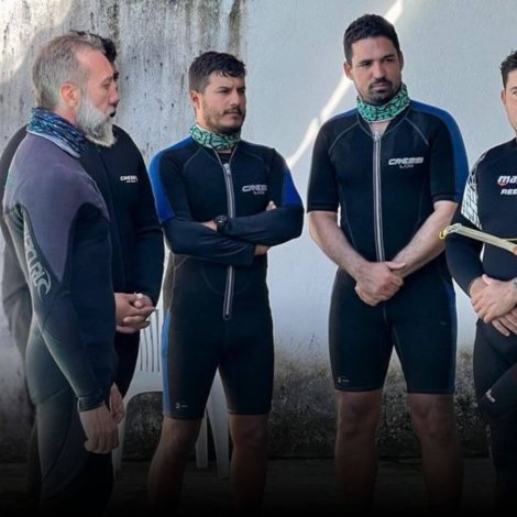 Confident scuba diving instructor leading a dive briefing with students before entering the water, representing leadership in the competitive dive instructor job market.