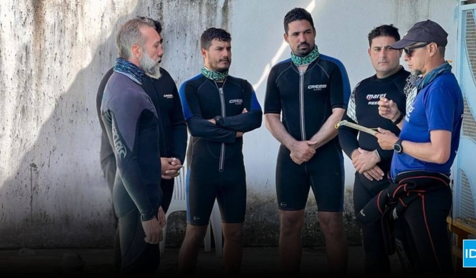 Confident scuba diving instructor leading a dive briefing with students before entering the water, representing leadership in the competitive dive instructor job market.