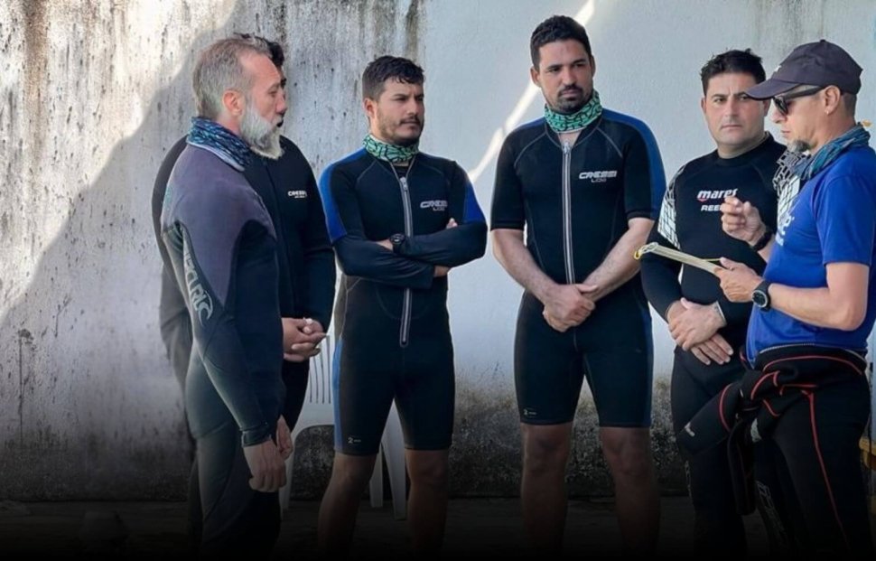 Confident scuba diving instructor leading a dive briefing with students before entering the water, representing leadership in the competitive dive instructor job market.