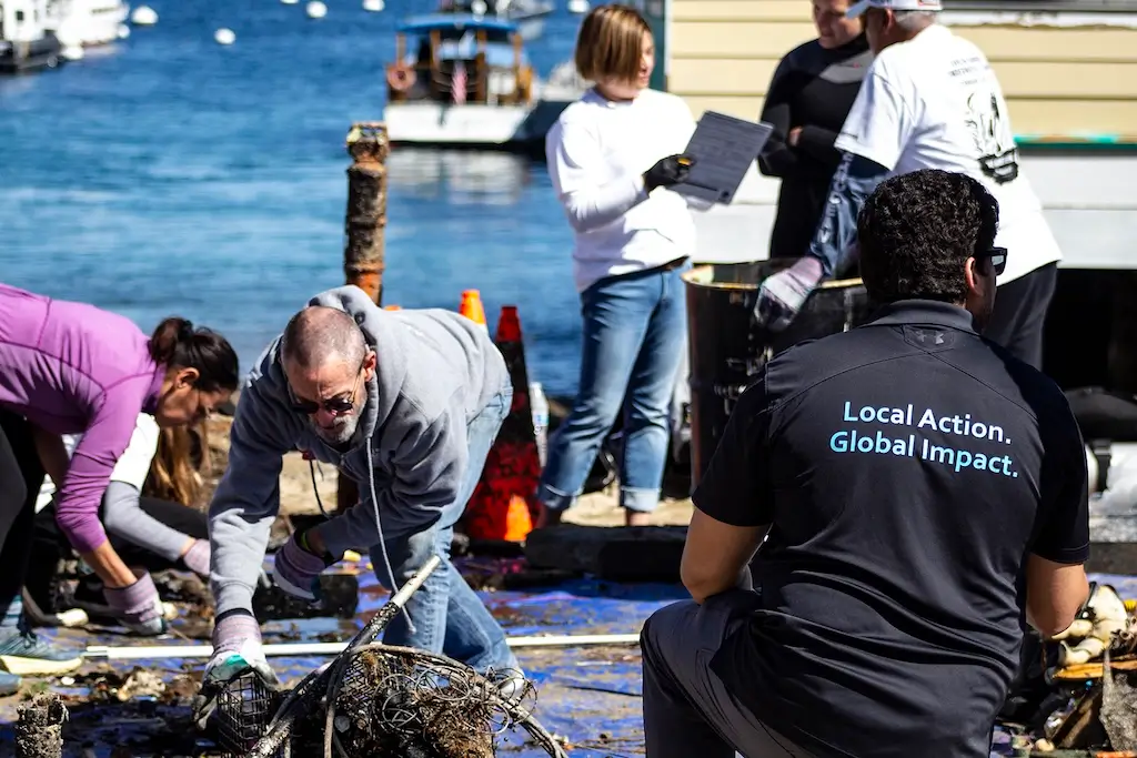 Ocean conservationists working together along a waterfront, collecting marine debris and discarded fishing gear to help protect the ocean and coastal environment
